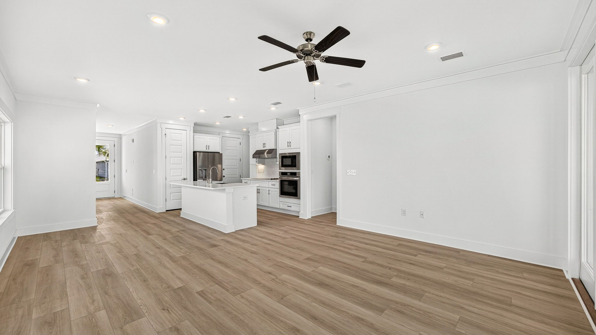 Open living room with EVP flooring and ceiling fan looking into kitchen.