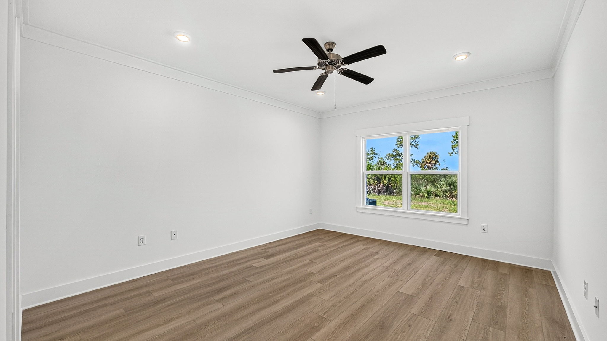 Primary bedroom with EVP flooring and ceiling fan and two windows.