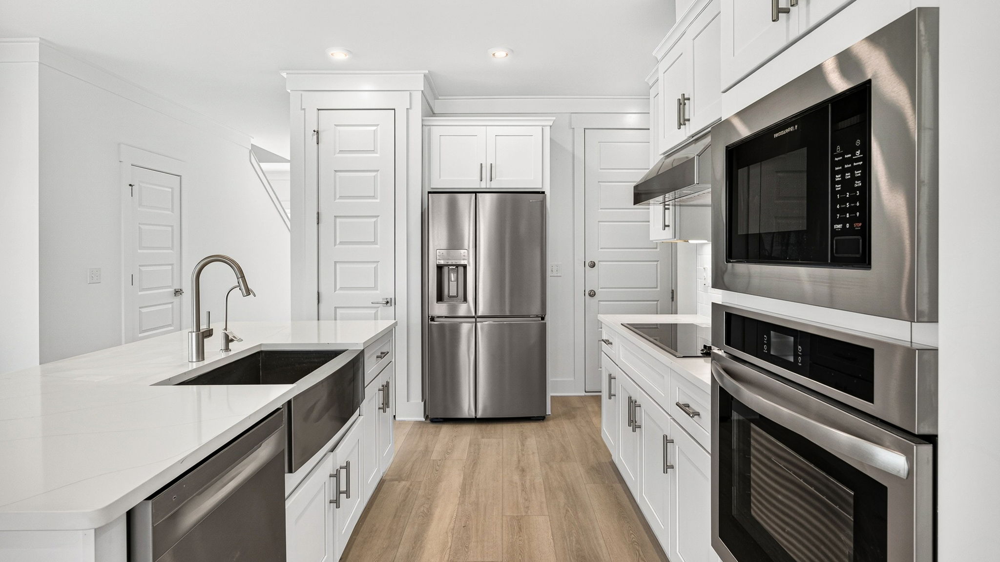 Open kitchen with island with quartz countertops and stainless-steel appliances and pantry.