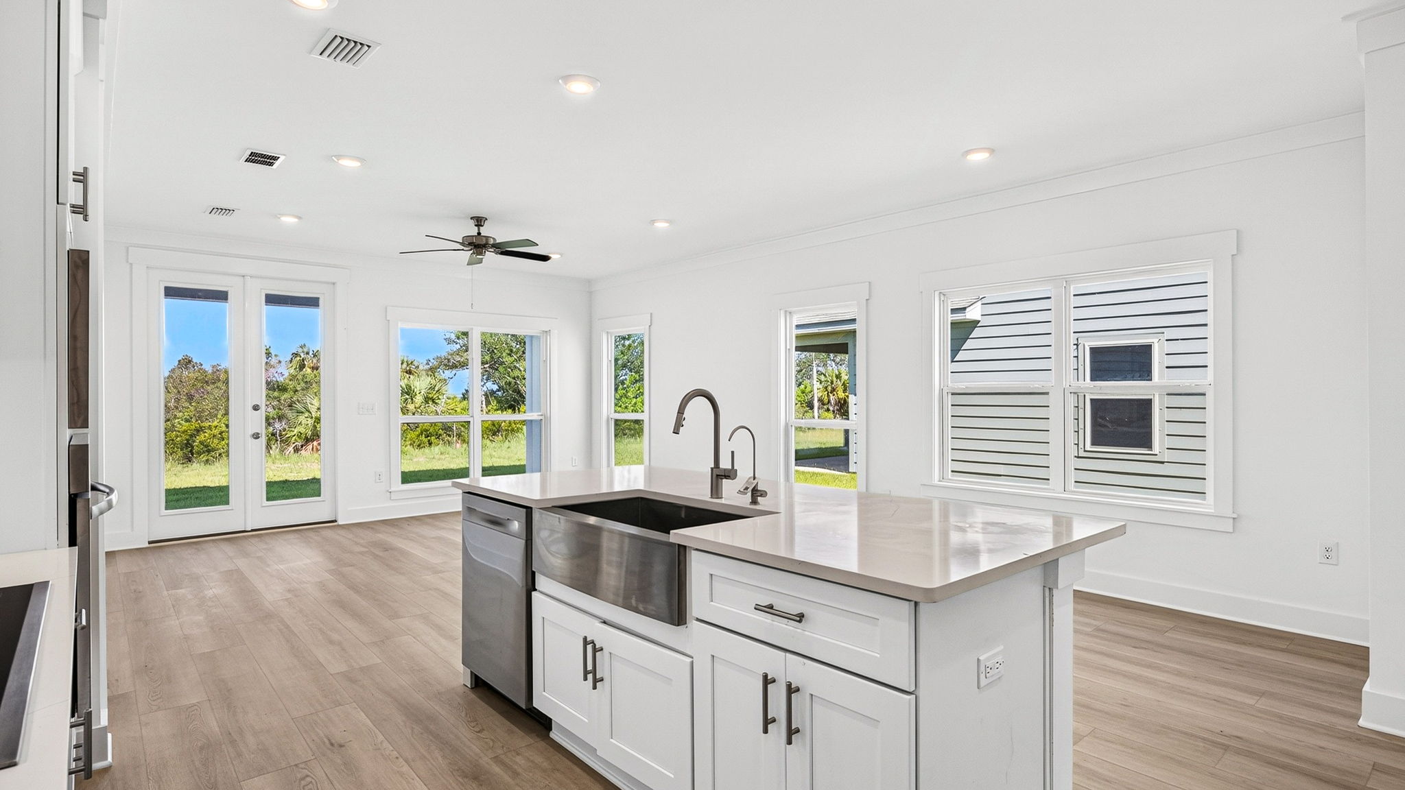Open kitchen with island with quartz countertops and stainless-steel appliances looking into living room.