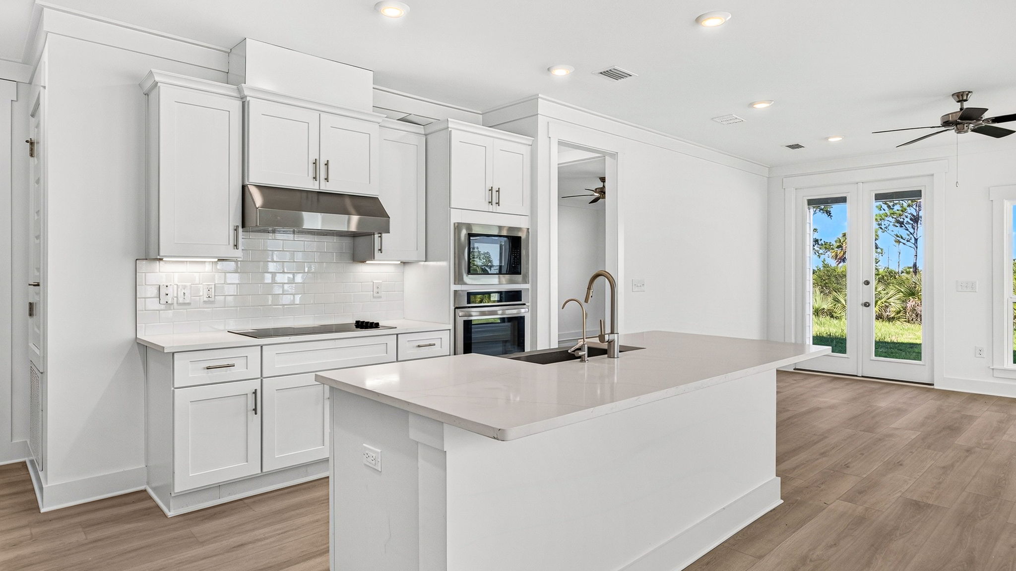 Open kitchen with island with quartz countertops and stainless-steel appliances looking into living room.