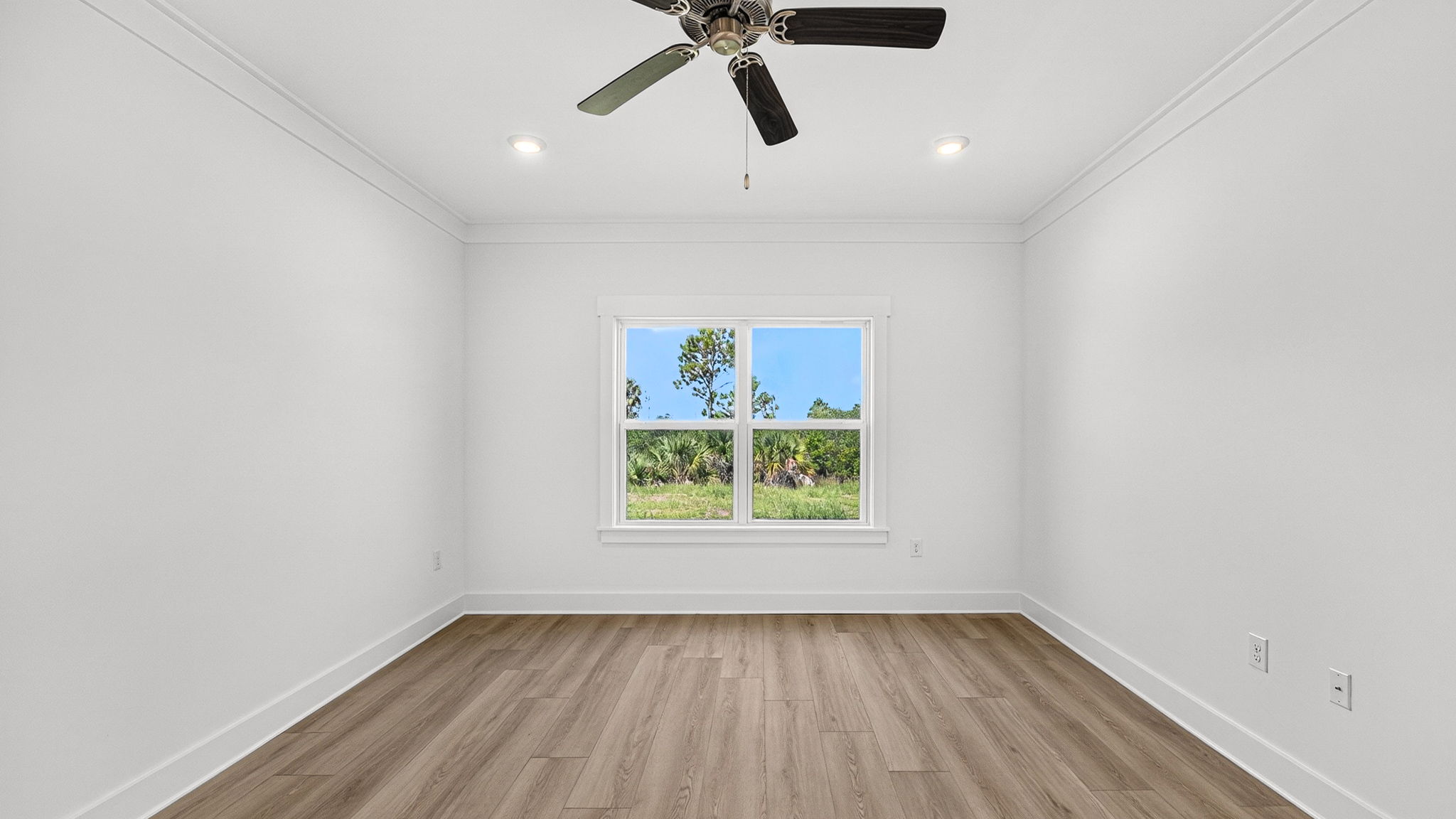 Primary bedroom with EVP flooring and ceiling fan and two windows.