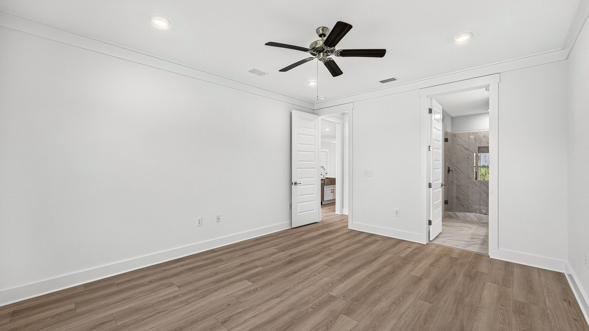 Primary bedroom with EVP flooring and ceiling fan and bathroom entrance.