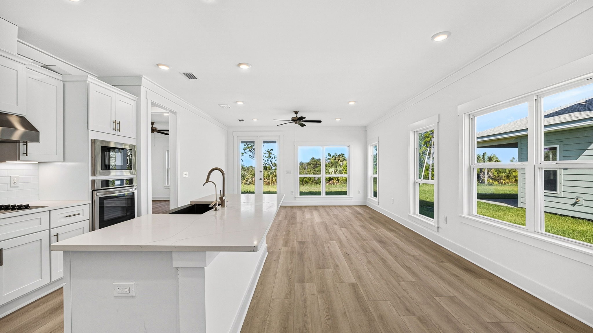 Open kitchen with island with quartz countertops and stainless-steel appliances looking into living room.