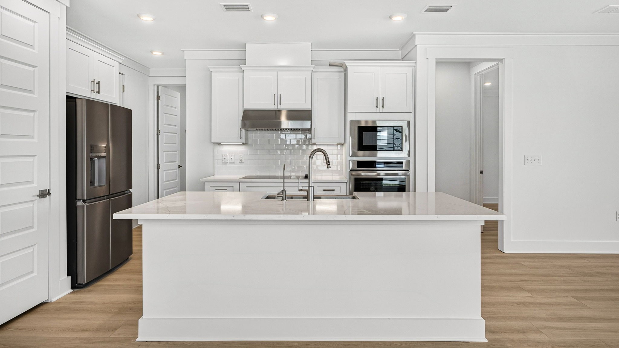 Open kitchen with island with quartz countertops and stainless-steel appliances.