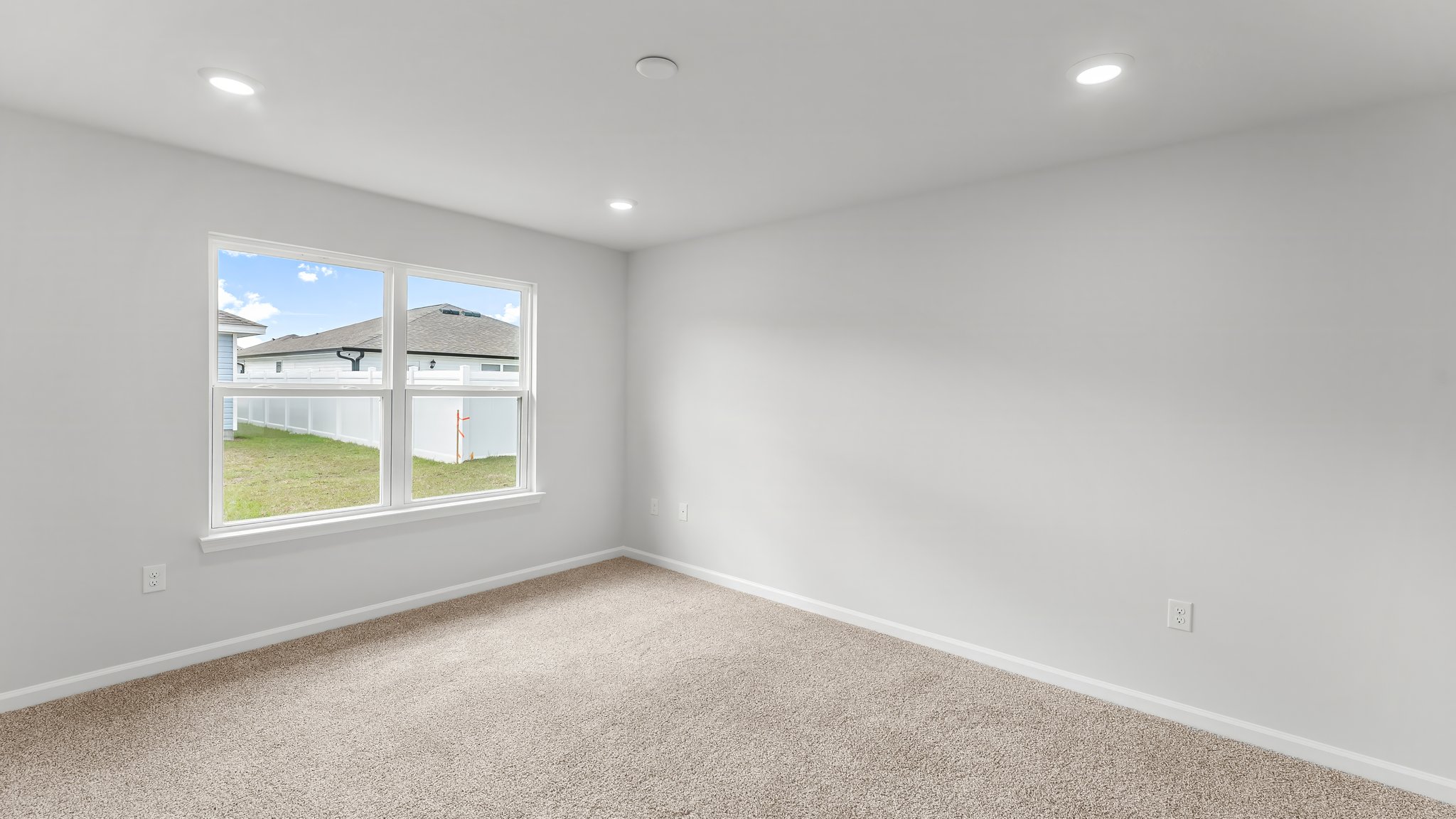 Primary bedroom with carpet flooring and two windows.