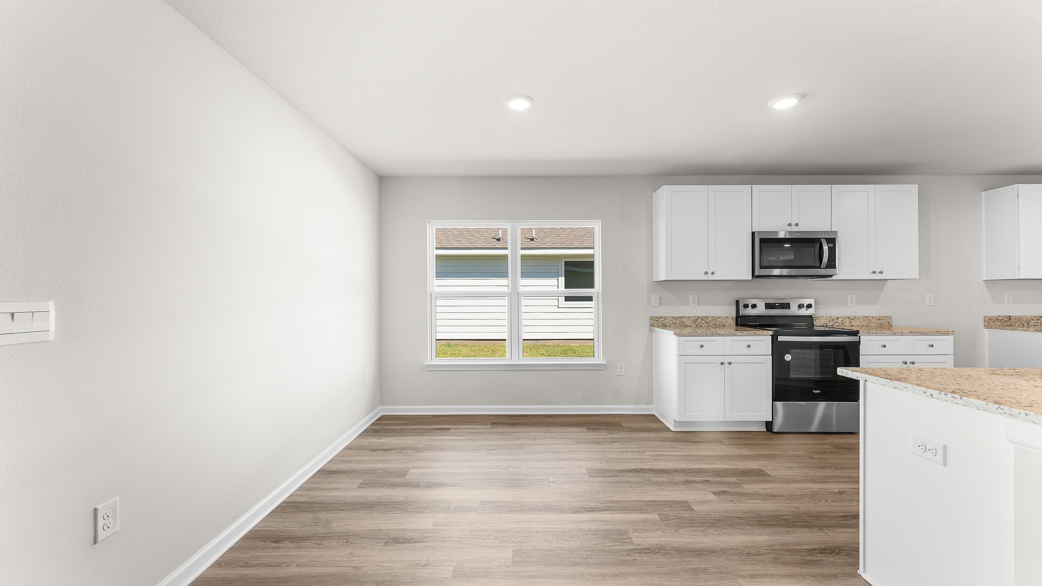 Kitchen with white cabinets and granite countertops and small dining area.