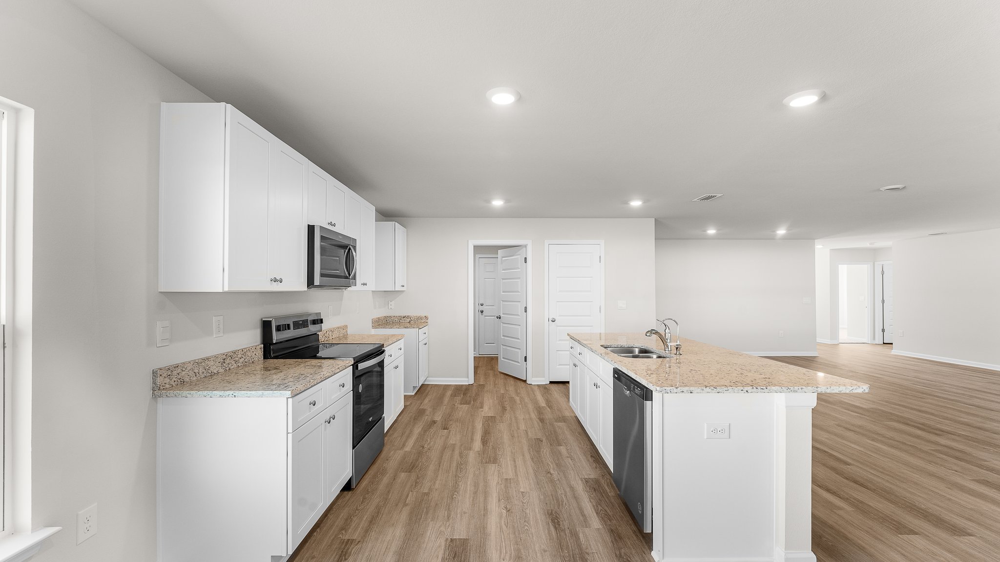 Kitchen with white cabinets and granite countertops and island and stainless-steel appliances and pantry.