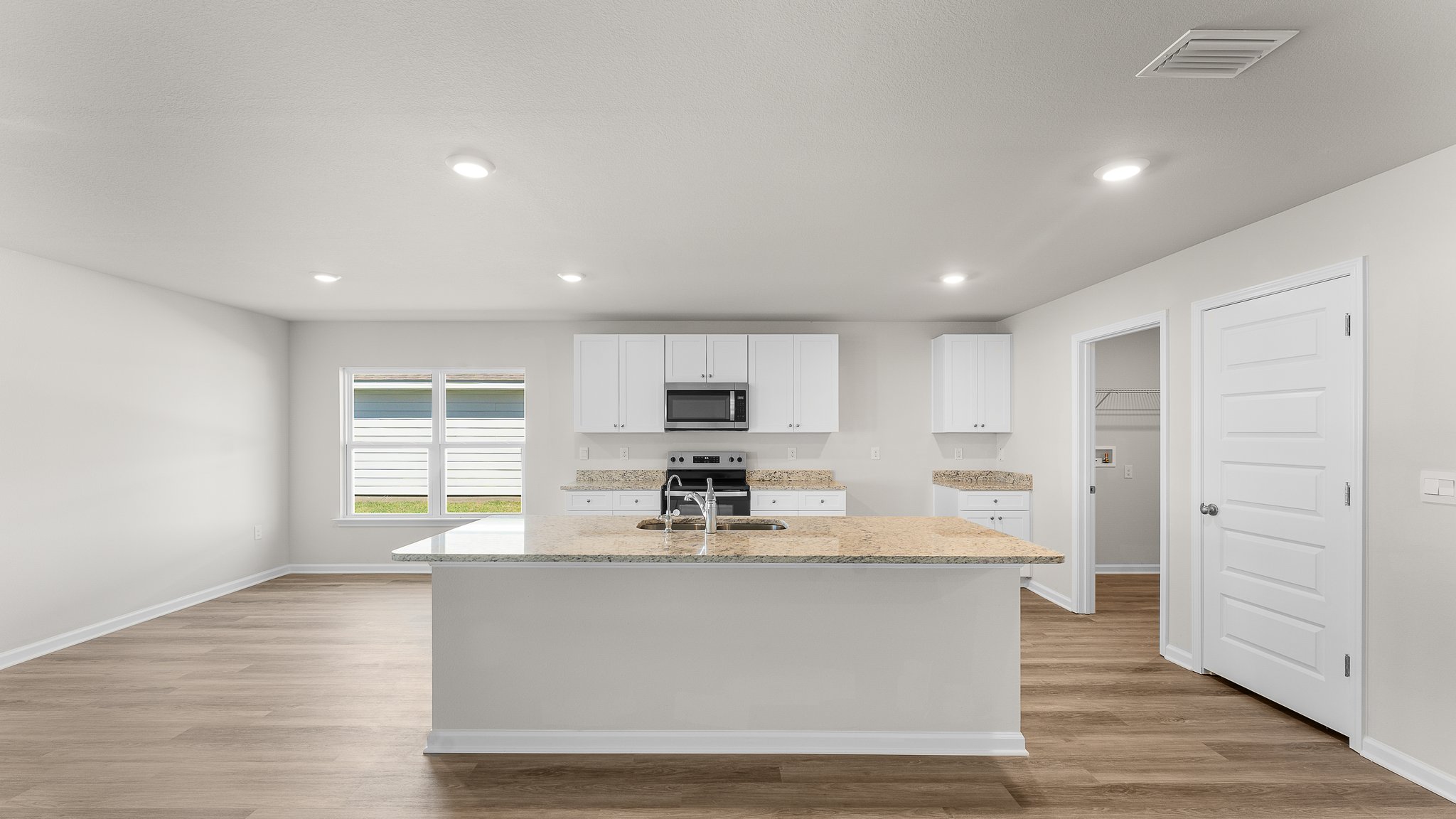 Kitchen with white cabinets and granite countertops and island and stainless-steel appliances and pantry.