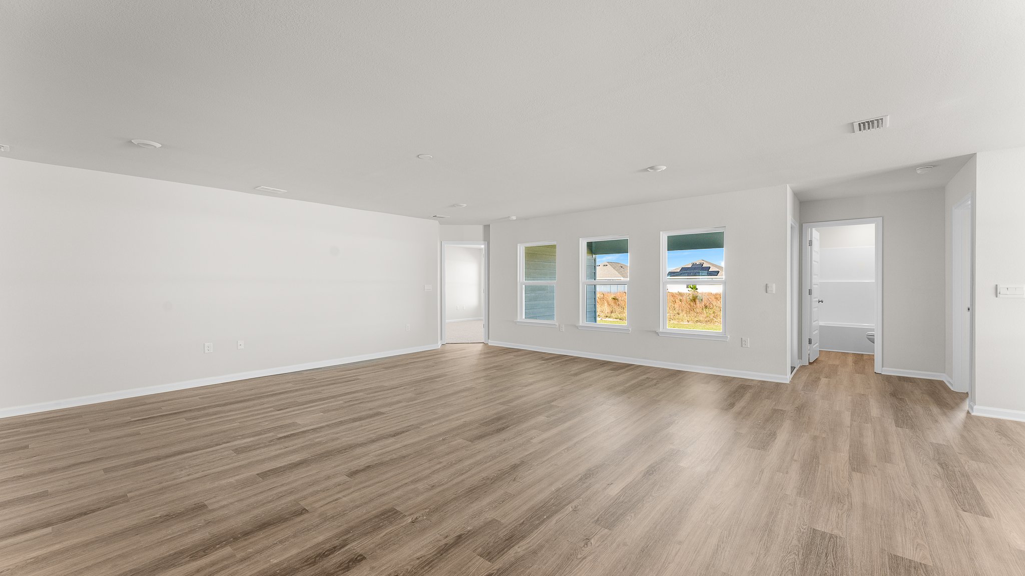 Open Living room with EVP flooring and 3 windows.