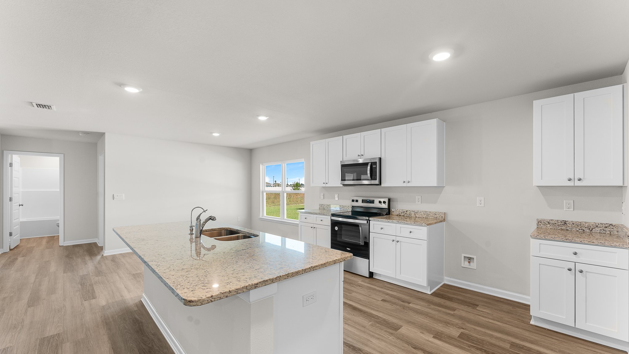 Kitchen with white cabinets and granite countertops and island and stainless-steel appliances.