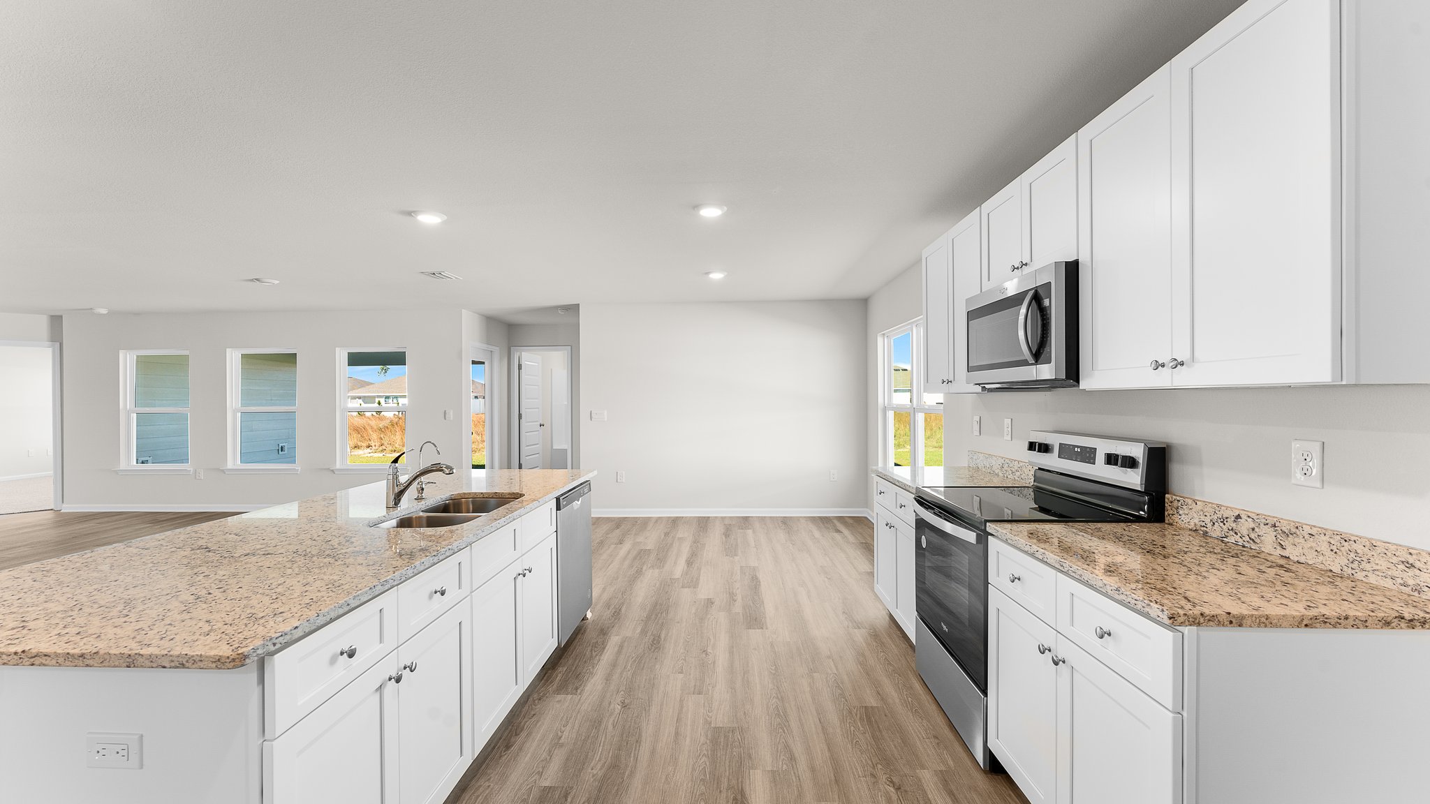 Kitchen with white cabinets and granite countertops and island and stainless-steel appliances.