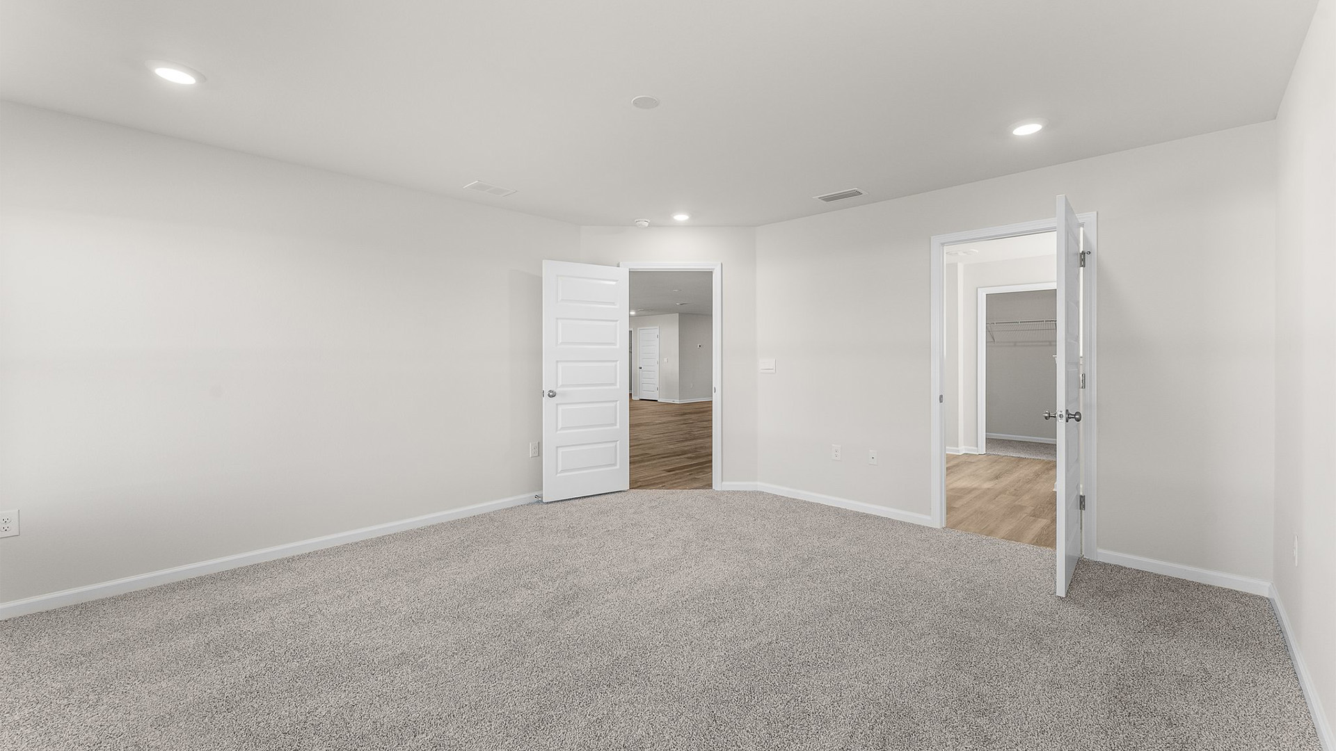 Primary bedroom with carpet floors and bathroom entrance.