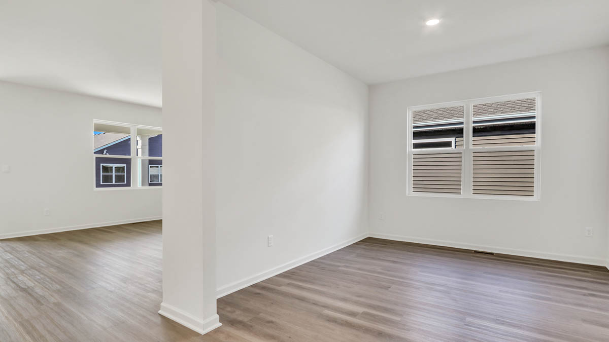 Room with hard wood flooring with windows.