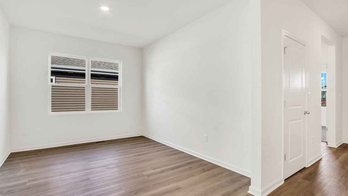 Room with hard wood flooring and big window.