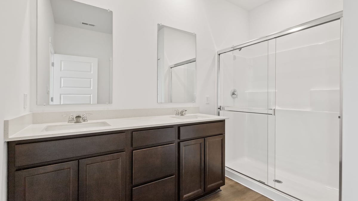 Dual vanity sinks with a walk in shower and a walk in closet.