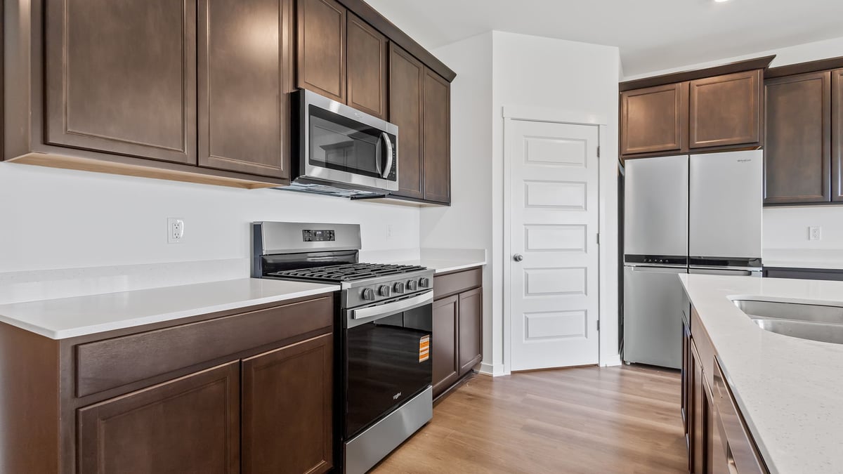 Kitchen with brown cabinets and a microwave and hard floors.