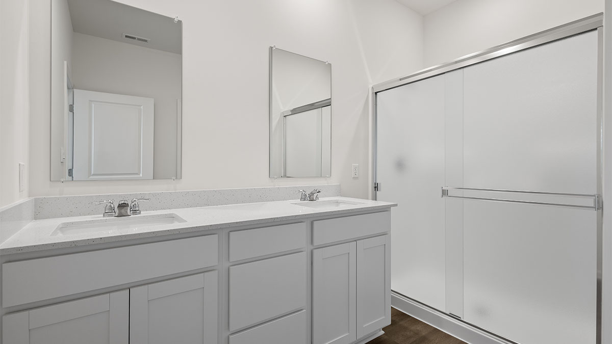 Dual vanity sinks with a walk in shower and walk-in closet.
