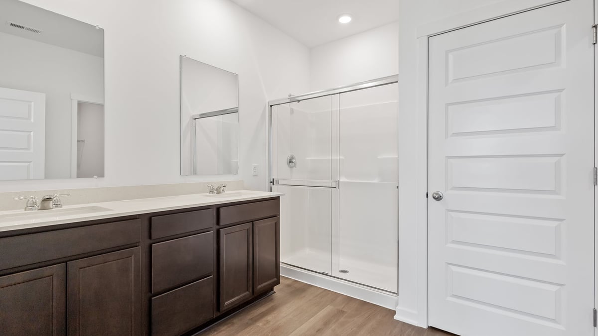 Primary bathroom with dual vanity sinks and a walk-in shower.