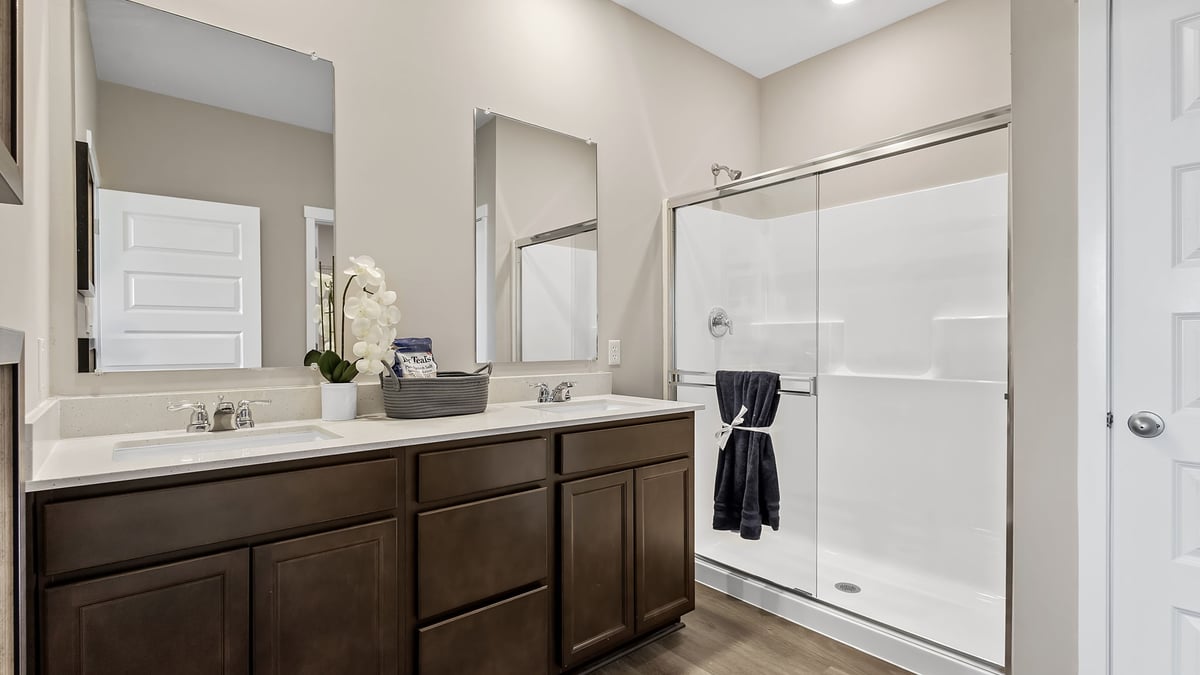 Primary bathroom with dual vanity sinks and a walk-in shower.
