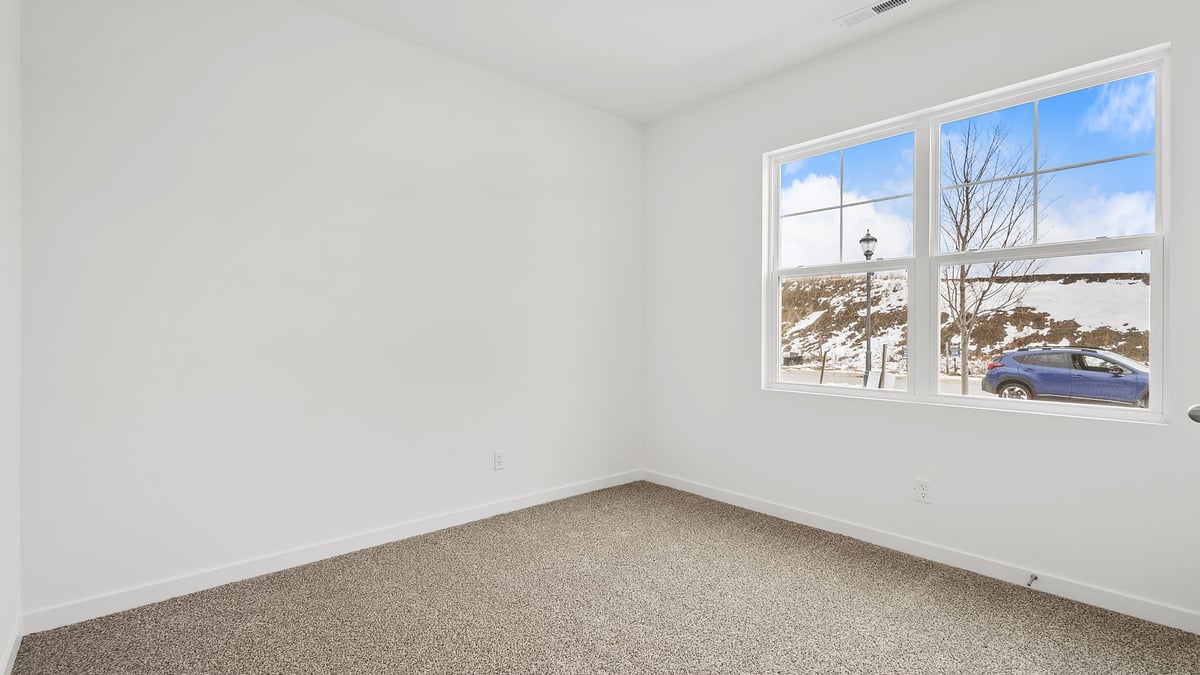 Bedroom with a big window and carpeted floors.