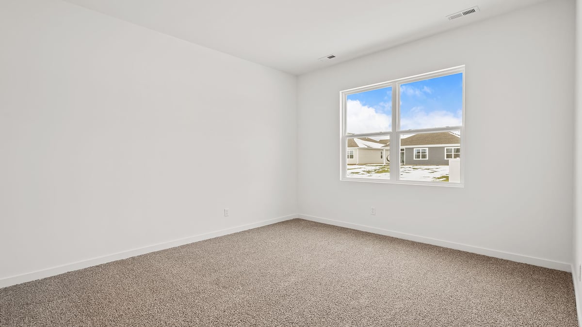 Bedroom with a big window and carpeted floors.