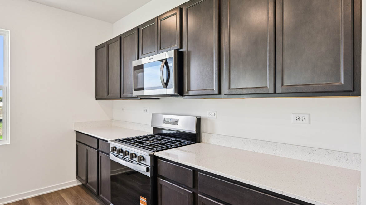 Kitchen brown cabinets and microwave and stove.