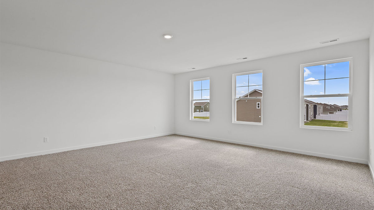 Primary bedroom with carpeted floors and three windows.