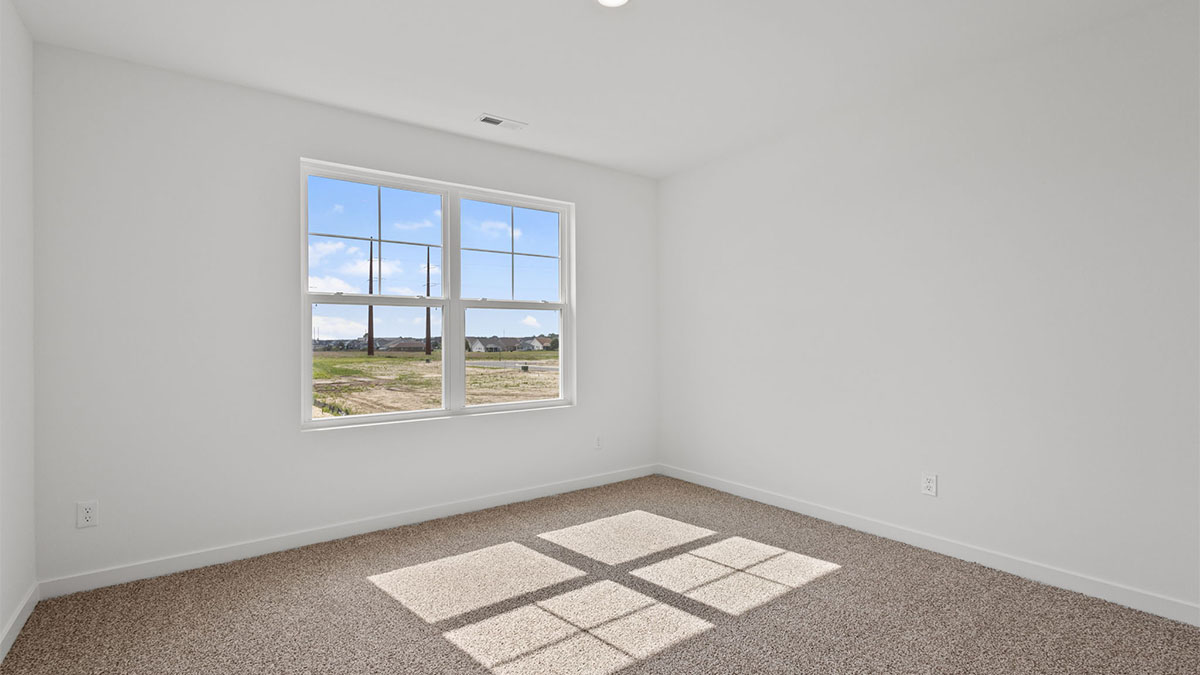 Bedroom with a big window and carpeted floors.