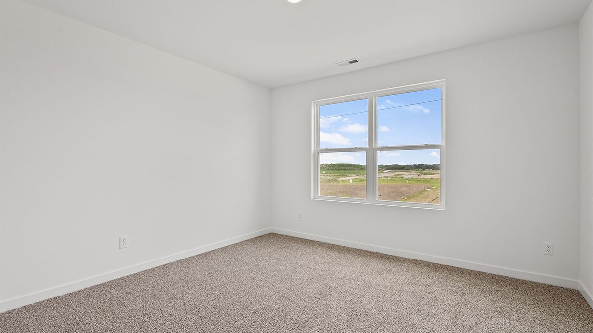 Bedroom with a big window and carpeted floors.