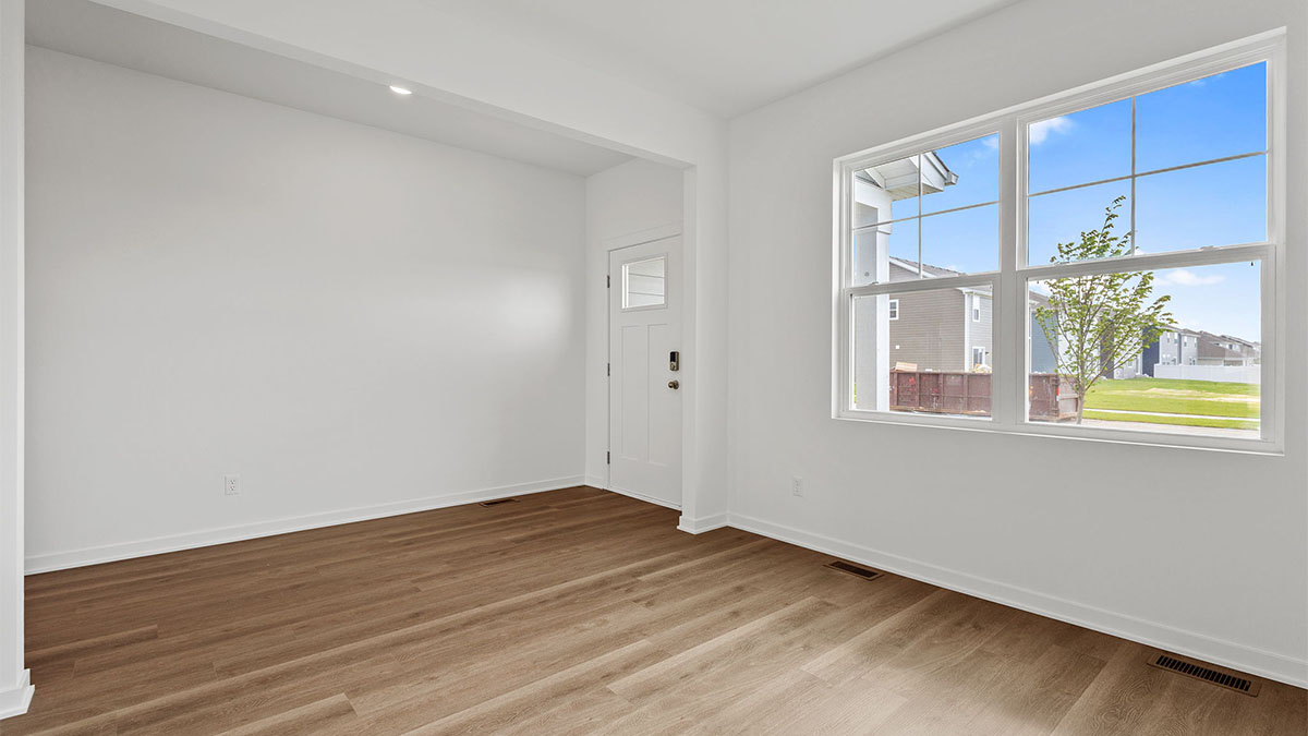 Front room with a big window and hard wood flooring.
