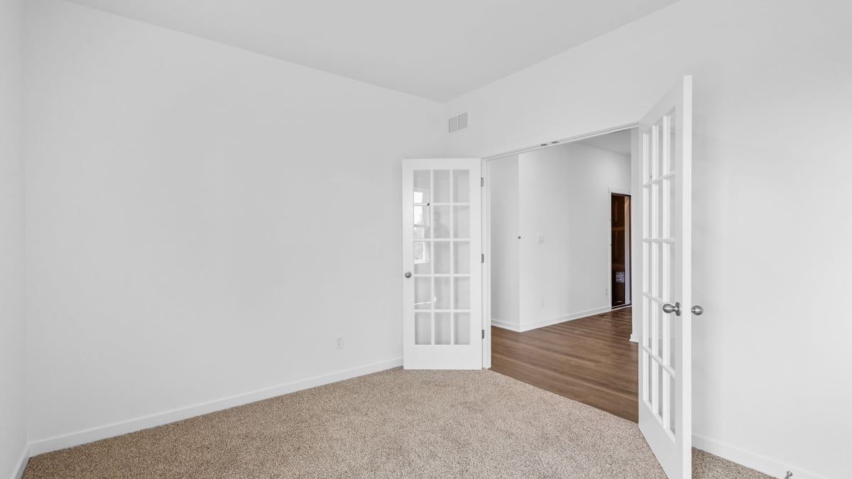 Carpeted room with french doors.