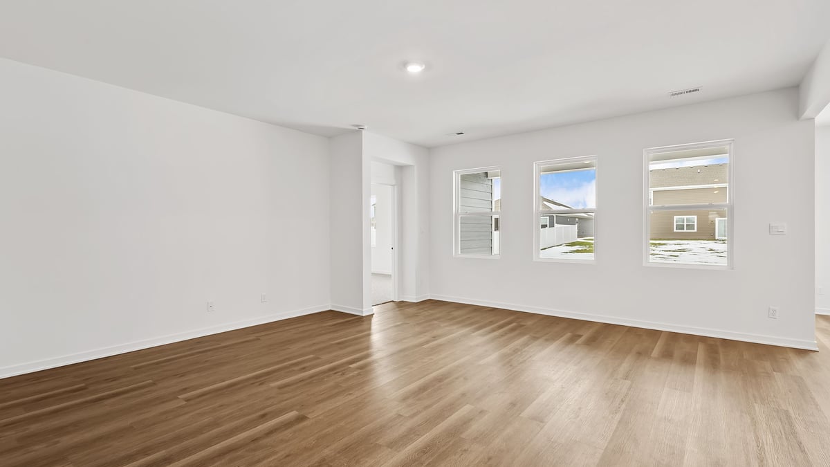 Living room area with hard wood floors with windows.