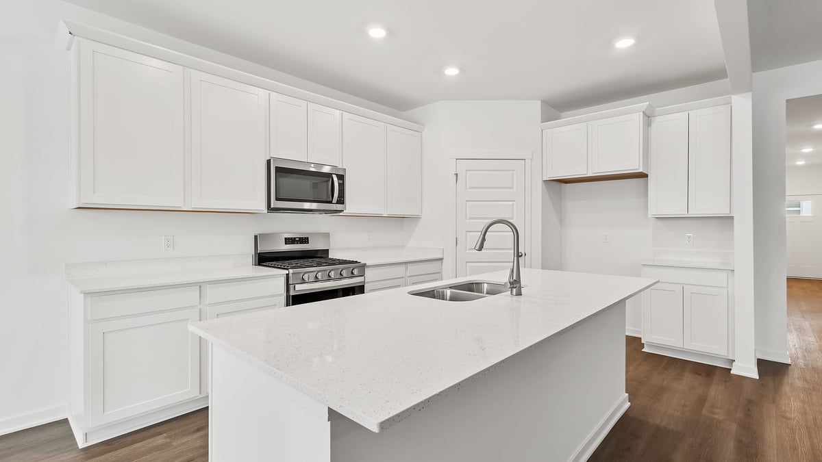 Kitchen with white cabinets and hard wood flooring.