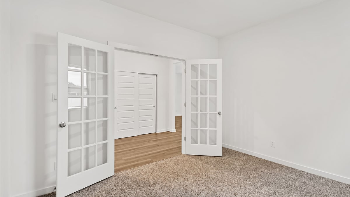Bedroom with carpeted floors and french open doors,