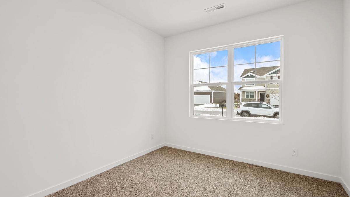 Bedroom with a big window and carpeted floors.