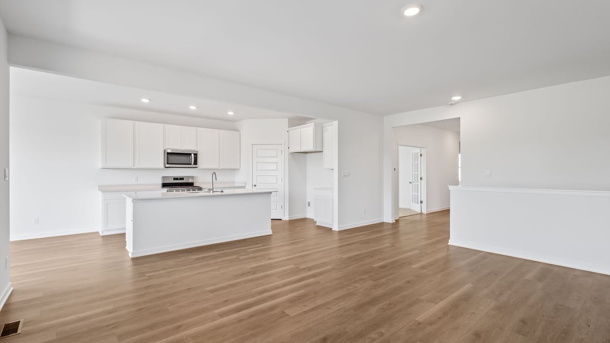 Living room area and kitchen area with hard wood floors.