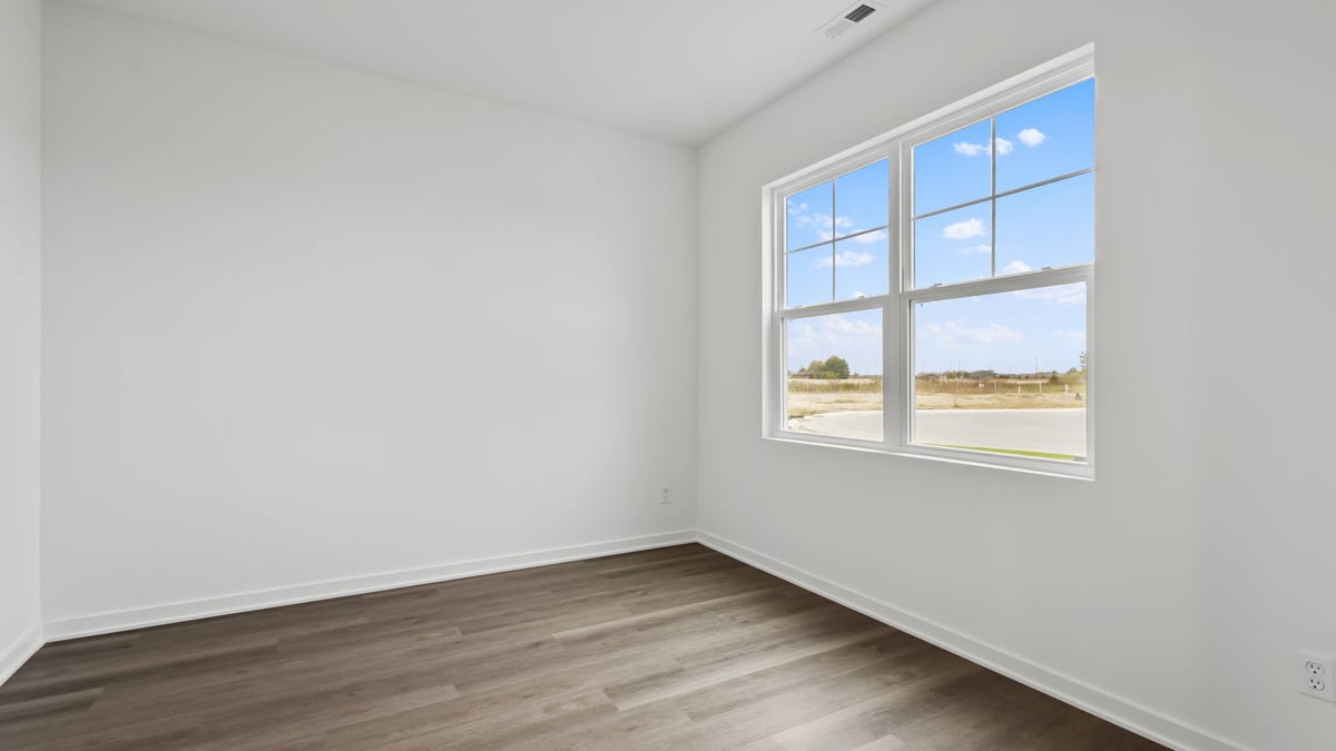 Front room of home with windows and hard wood flooring.