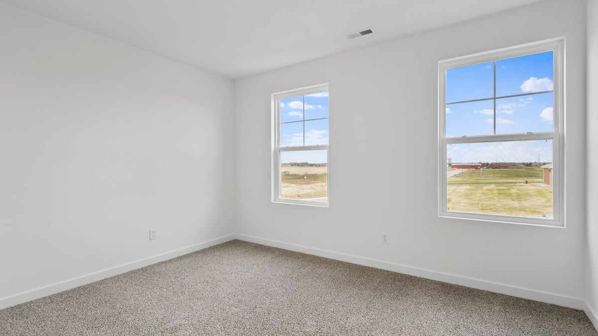 Bedroom with two windows and carpeted.