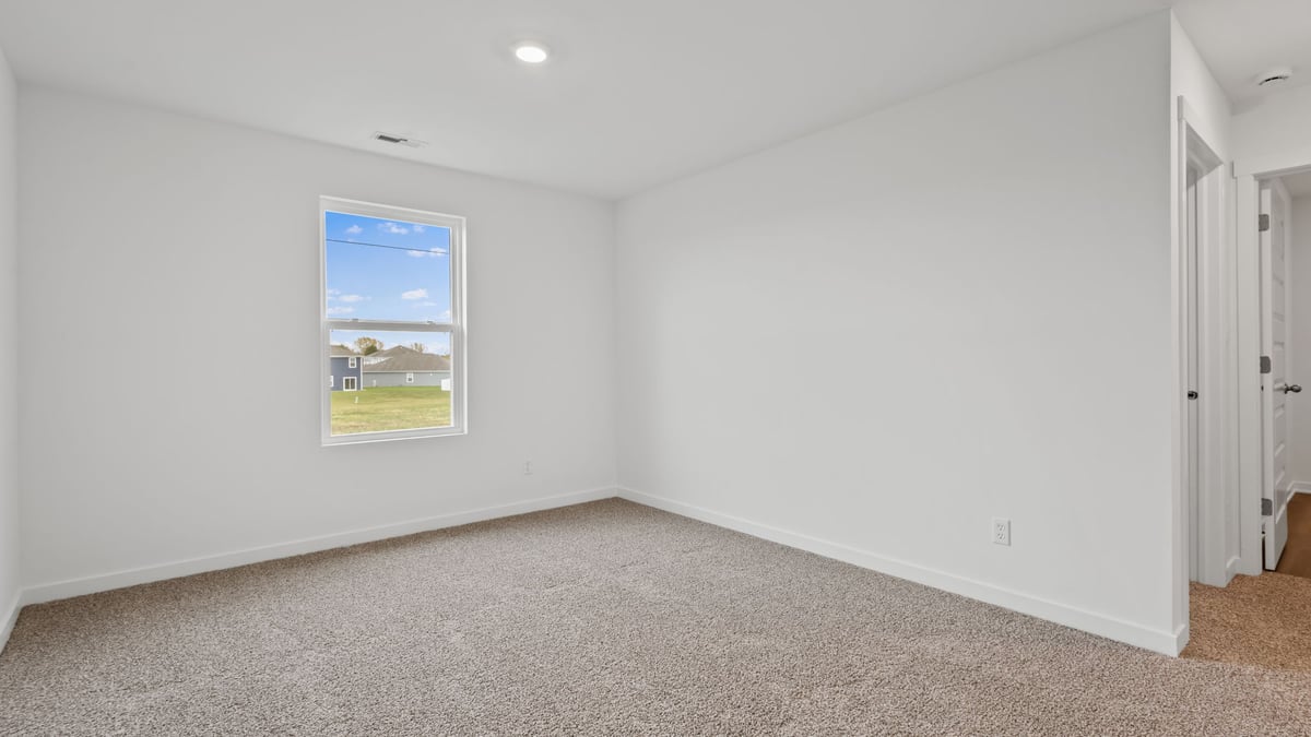 Bedroom with window and carpeted floors.