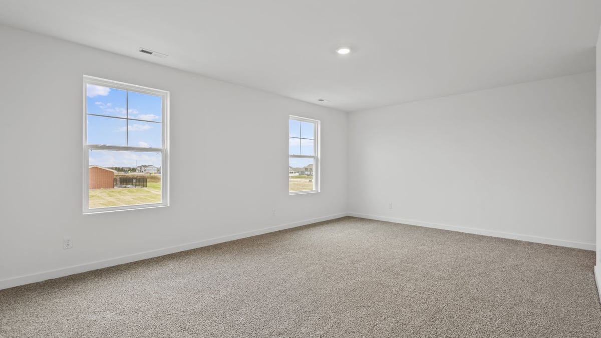 Bed room with two windows and carpeted floors.