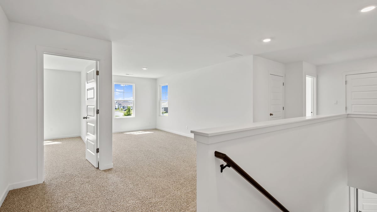 Upstairs area with view of loft area and carpeted floors.