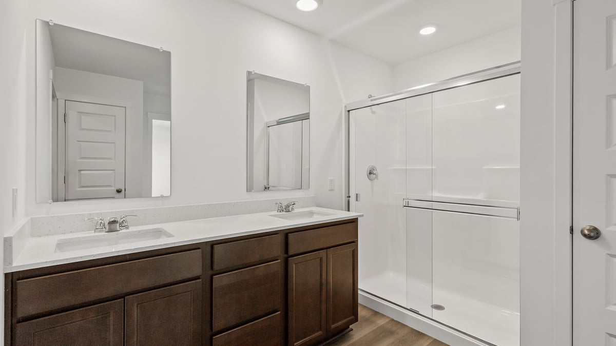 Primary bathroom with dual vanity sinks and a walk-in shower.