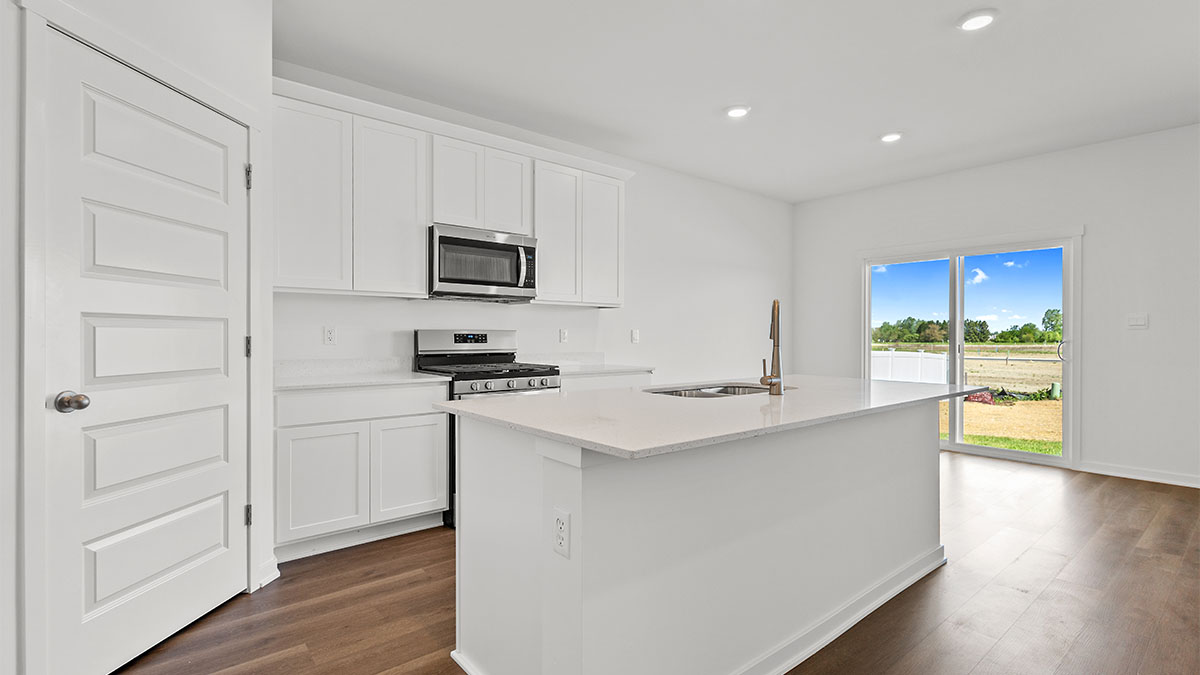 Kitchen with white cabinets and view of dining area.