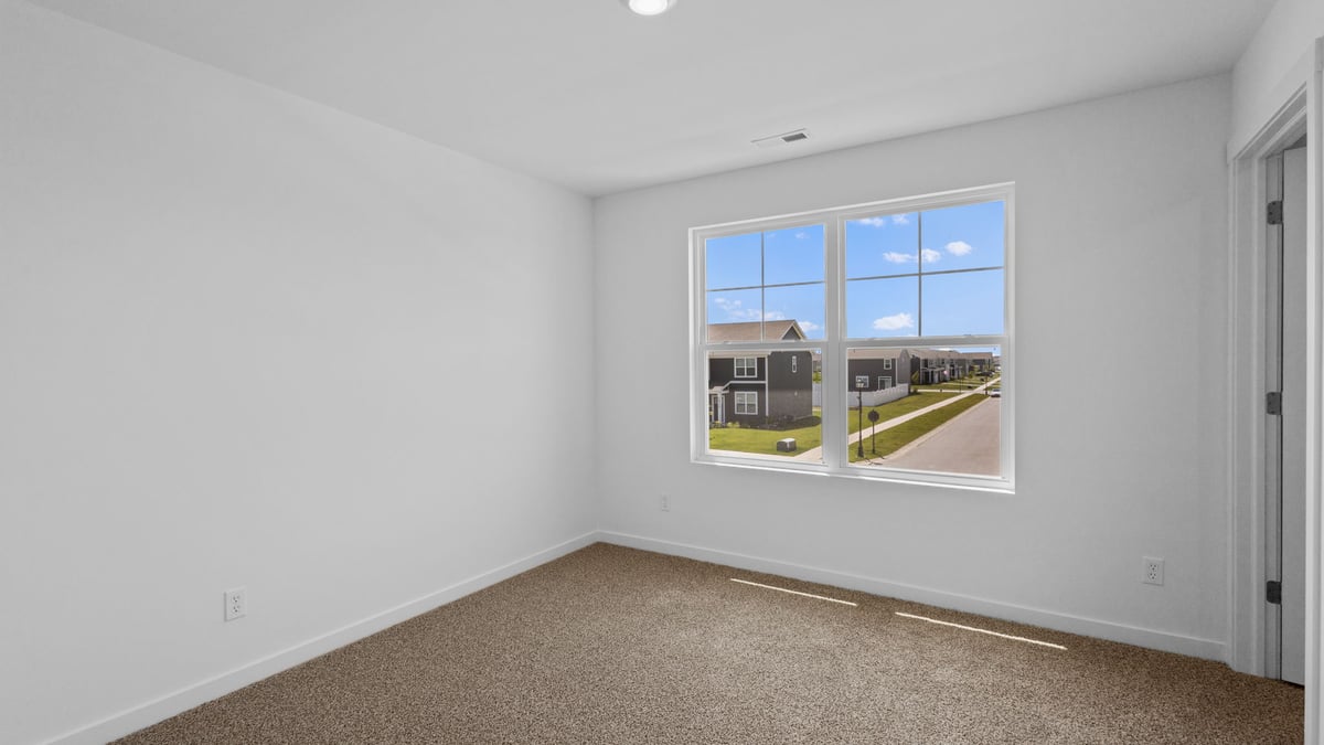 Bedroom with a big window and carpeted floors.