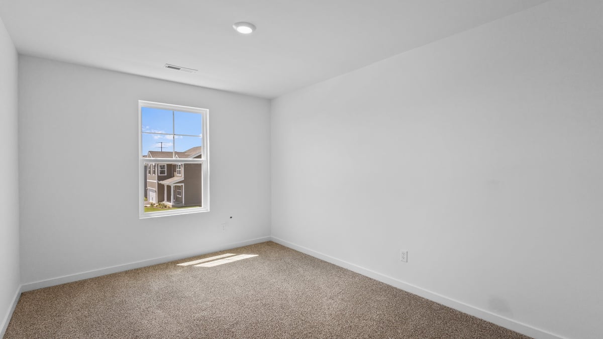 Bedroom with a side window and carpeted floors.