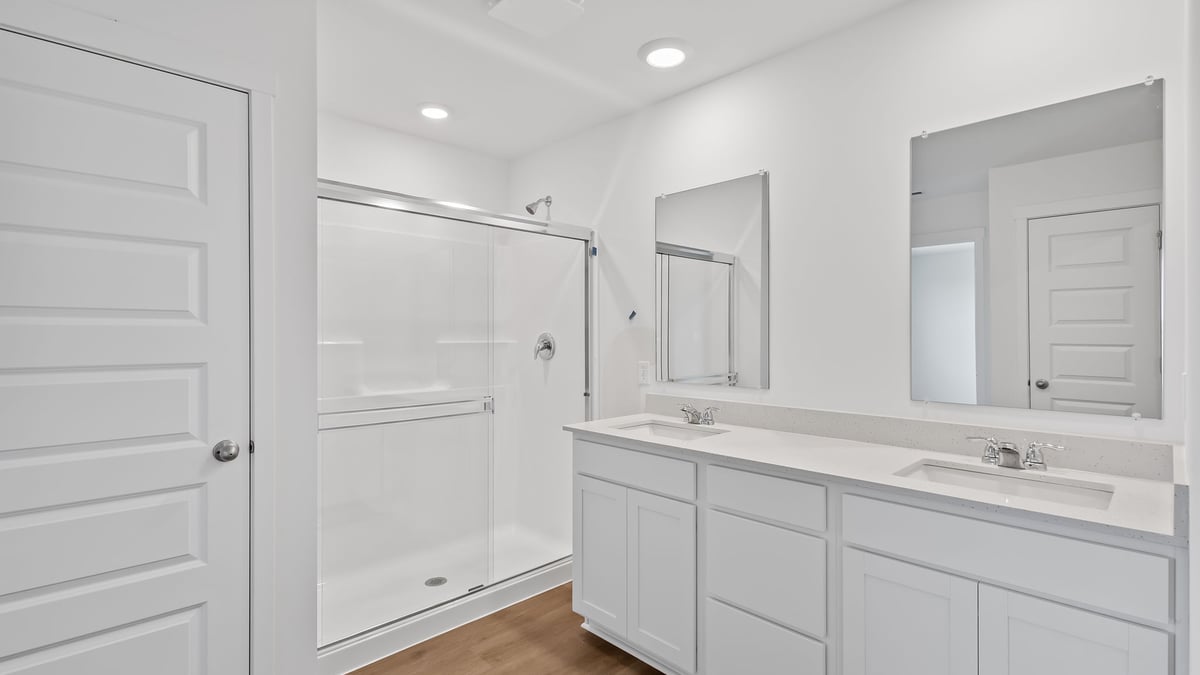 Primary bathroom with dual vanity sinks and a walk-in shower.