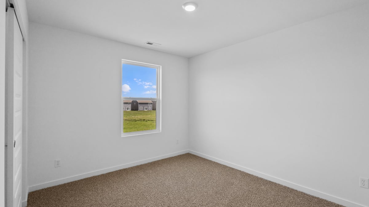 Bedroom with a side window with carpeted floors and a side window.