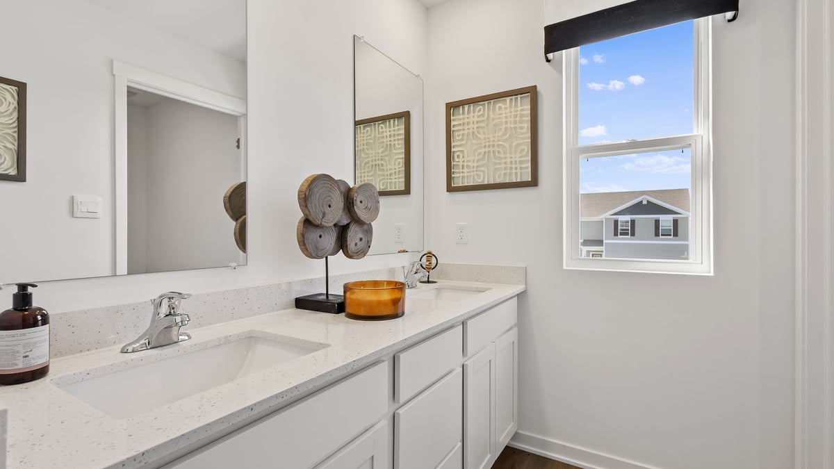 Bathroom with dual vanity sinks and a side window.