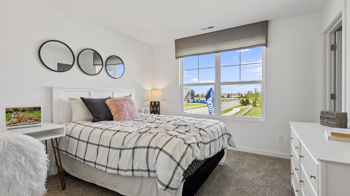 Bedroom with a big window and carpeted floors.